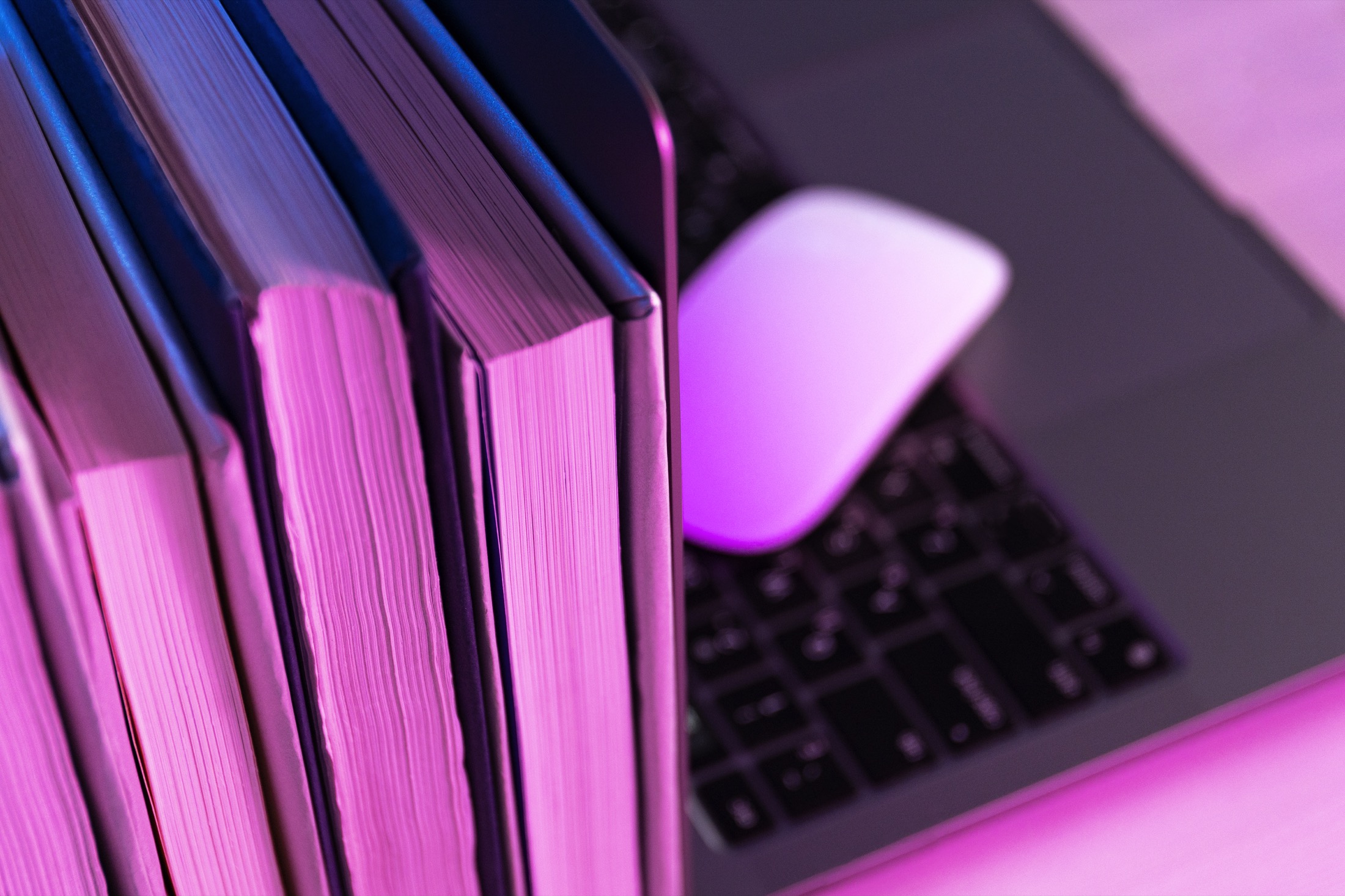 Books beside a computer in soft pink and blue light
