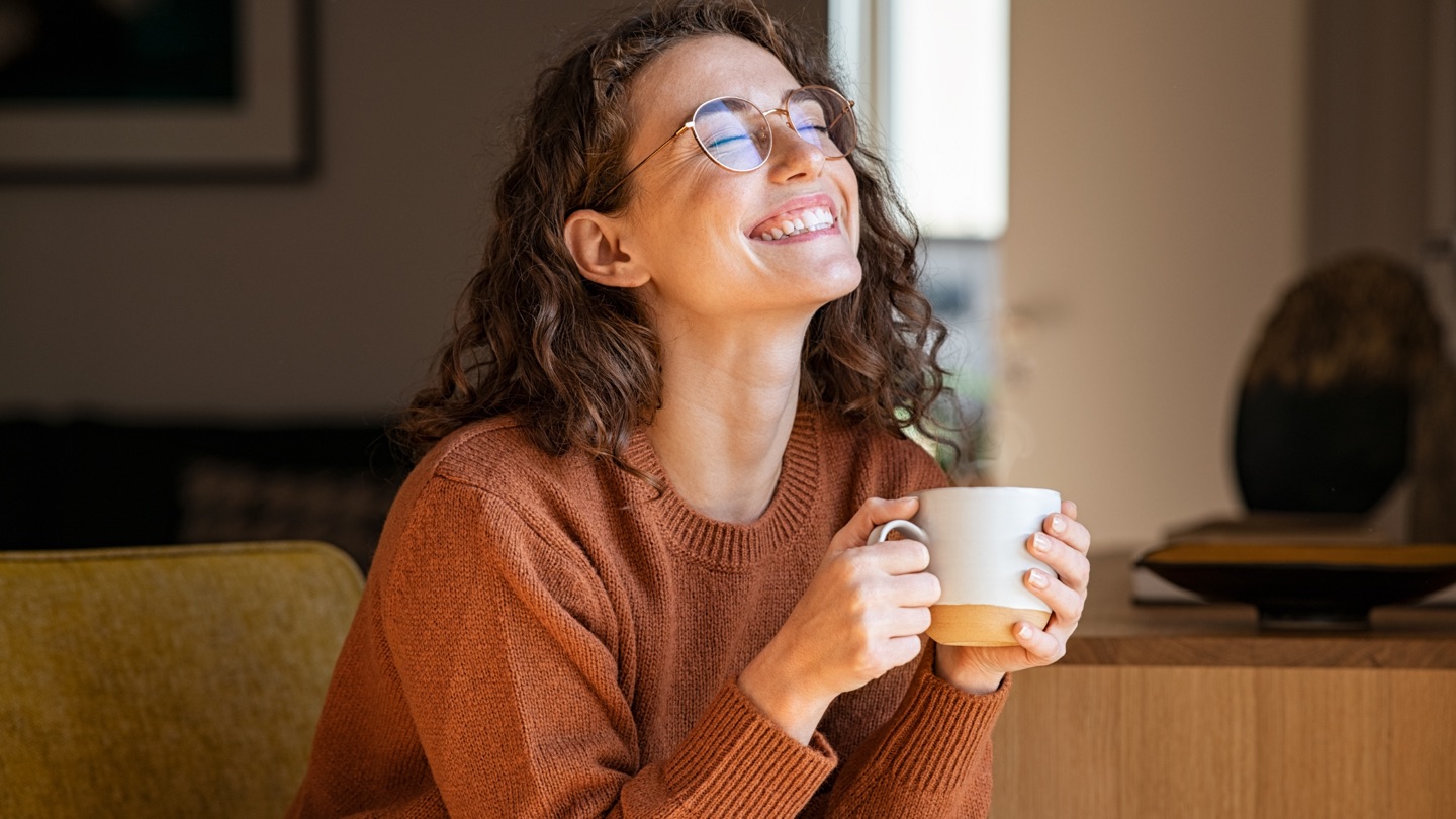 A relaxed business owner smiling with a warm drink