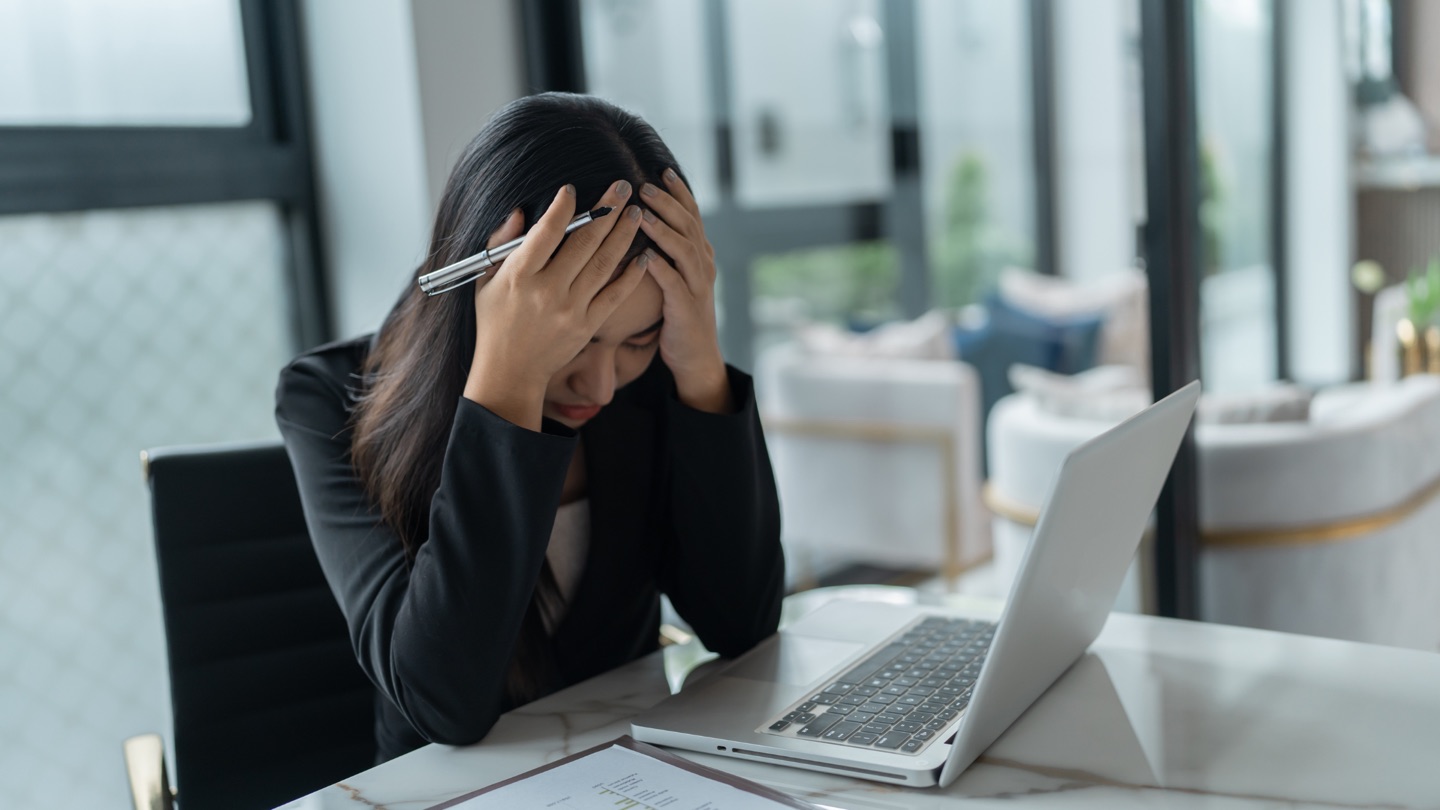 A business owner feeling overwhelmed at her laptop